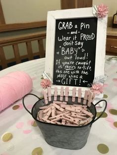 a bucket filled with baby's clothes sitting on top of a table next to a chalkboard