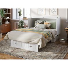 a white bed sitting on top of a wooden floor next to a rug and window