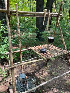 a wooden swing with pots and pans on it in the woods next to trees