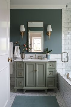 a bathroom with green walls and white tile on the floor, along with two sinks