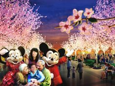 the mickey mouse family is posing for a photo in front of cherry blossom trees at night