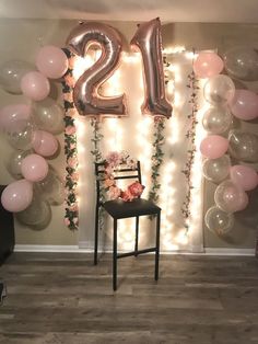 a chair and balloons in front of a wall with the number twenty