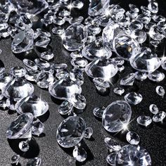 many clear diamonds are scattered on a black surface