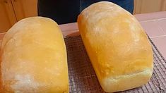 two loafs of bread sitting on top of a cooling rack next to each other