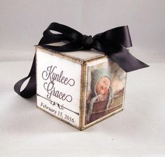 a baby's birth announcement box with a black ribbon tied around it and an image of a baby in a basket