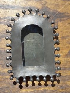 a metal frame with balls around it on a wooden surface and a mirror in the middle