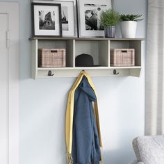 a coat rack with two pictures on it next to a white chair and a blue blanket