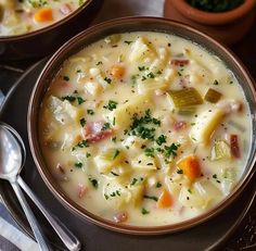 two bowls filled with soup sitting on top of a table next to silverware and spoons