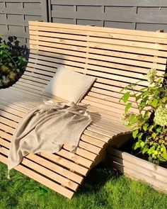 a wooden bench sitting in the grass next to some plants