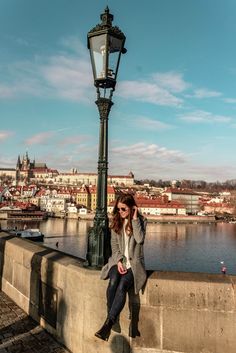 a woman is sitting on a wall next to a lamp post