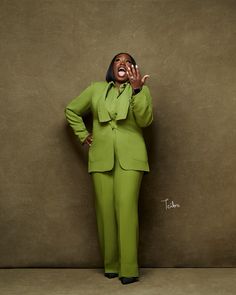 a woman in a green suit is posing with her hands on her face and mouth