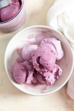 a bowl filled with pink ice cream next to a container of yogurt on a table