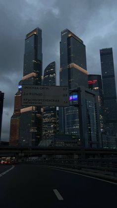 the city skyline is lit up at night, with skyscrapers in the foreground