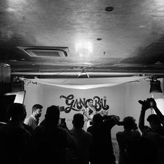 a group of people standing in front of a white wall with graffiti on the walls