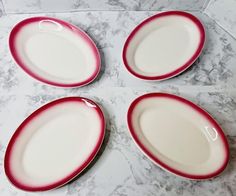 four red and white plates sitting on top of a marble counter