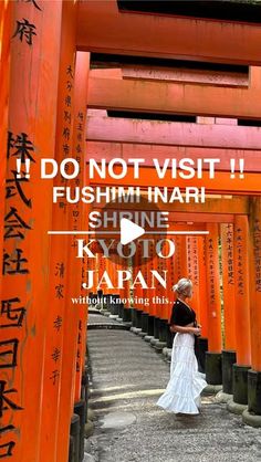 a woman in a white dress standing under an orange tori tori gate with japanese writing on it