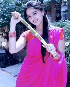 a woman in a pink sari holding a bamboo stick