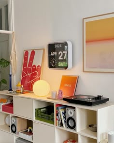 a white shelf with various items on it and a clock mounted to the wall behind it