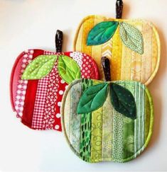 three apple shaped pot holders with green leaves and red, yellow, and orange designs