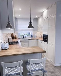 two chairs are sitting in front of the kitchen counter and island with stools on it