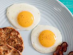 two fried eggs and some bacon on a plate