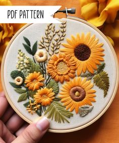 someone is holding up a hand embroidery pattern with sunflowers on it