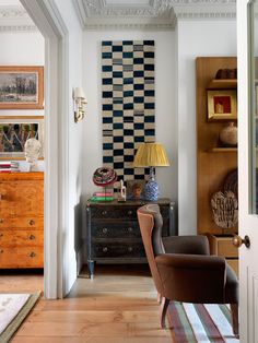 a living room filled with furniture and a checkered wall hanging on the wall above it