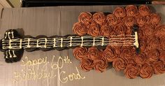 a guitar shaped birthday cake with chocolate icing and frosting swirls on it