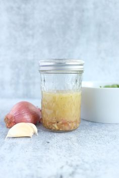 a jar filled with food sitting next to a garlic and an onion on a table