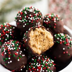 a white bowl filled with chocolate covered donuts and sprinkles on top