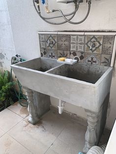 an old sink in the middle of a tiled wall with two faucets above it