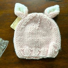 a knitted hat with ears on top of a wooden table next to a plastic bag