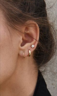 a close up of a person's ear with an earring on it and a flower in the middle