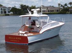 a red and white boat in the middle of water with palm trees in the background