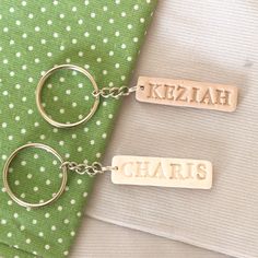 two personalized keychains sitting next to each other on a green and white cloth