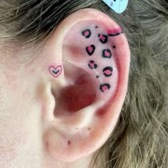 a girl has her ear painted with pink and black hearts on the inside of it