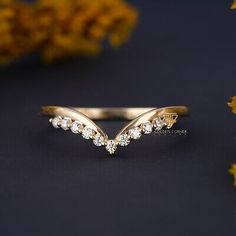 a gold ring with white stones on it and some yellow flowers in the foreground