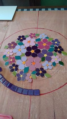 a wooden table topped with lots of different colored paper flowers on top of each other