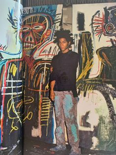 a man standing in front of a wall with graffiti on it's walls and another painting behind him