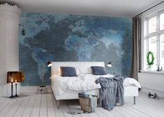 a white bed sitting in a bedroom next to a large map on the wall behind it