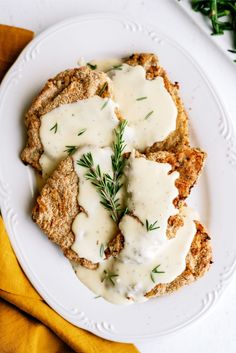 a white plate topped with meat covered in gravy