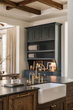 a kitchen with dark wood cabinets and gold faucets on the countertop, along with a white sink