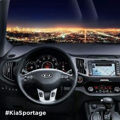 the interior of a car with city lights in the background and an electronic display on the dashboard