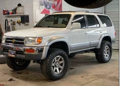 a white suv parked in a garage next to a tire changer and some tires