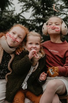 three children sitting on a bench with candy canes in their mouths and nose rings