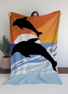 a woman is holding up a blanket with an image of a dolphin jumping out of the water