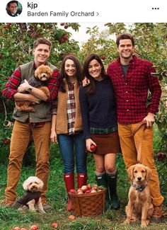 an image of people posing for a photo with their dogs and apples in the background