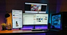 two computer monitors sitting on top of a wooden desk