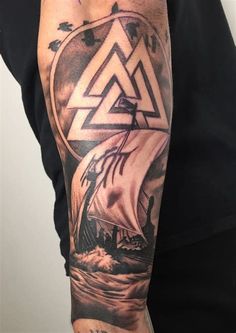 a man's arm with a ship on it and an illuminate triangle in the middle