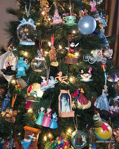 the christmas tree is decorated with many different disney figurines and ornaments on it